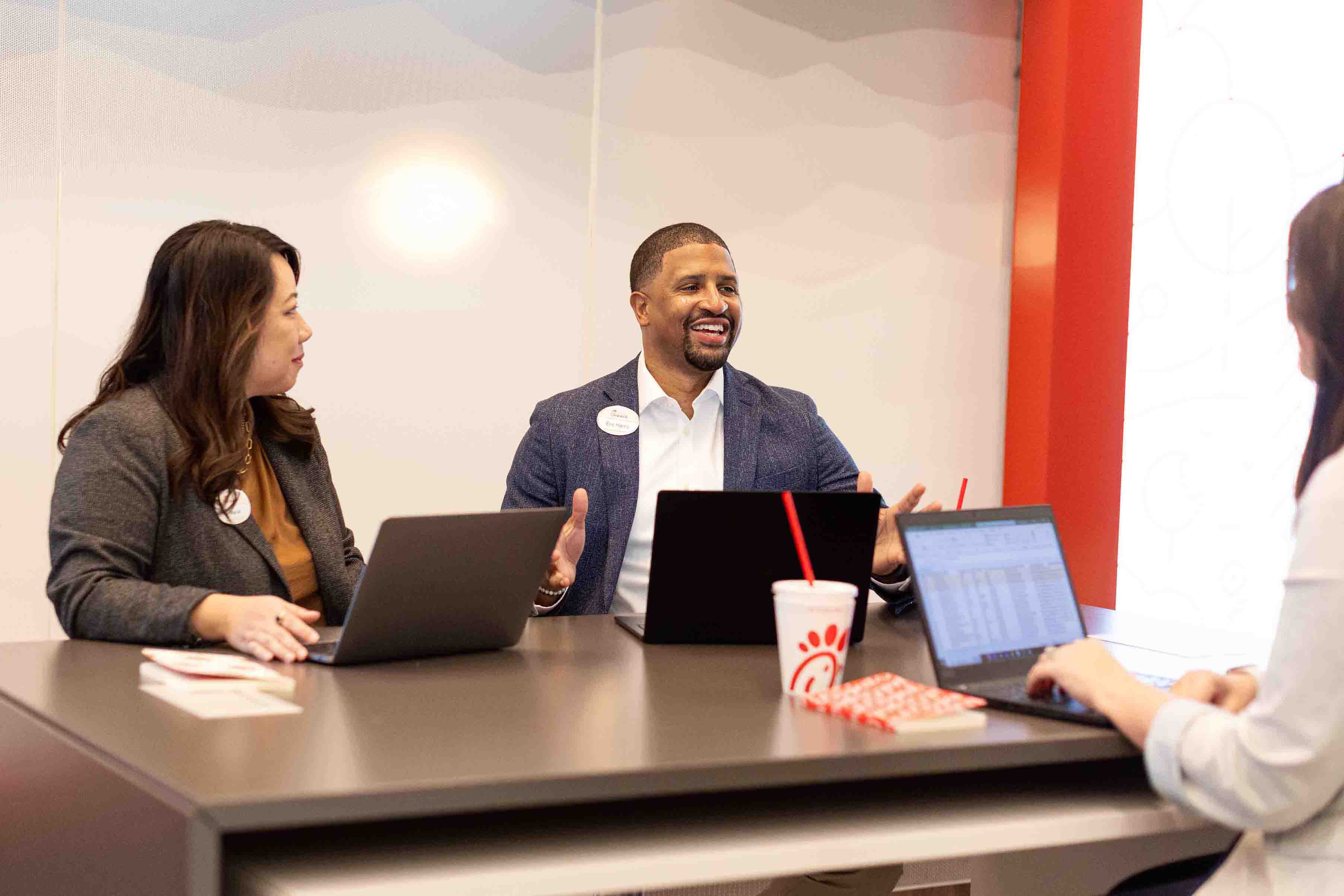 Chick-fil-A, Inc employees sitting at a table with their computer smiling and talking