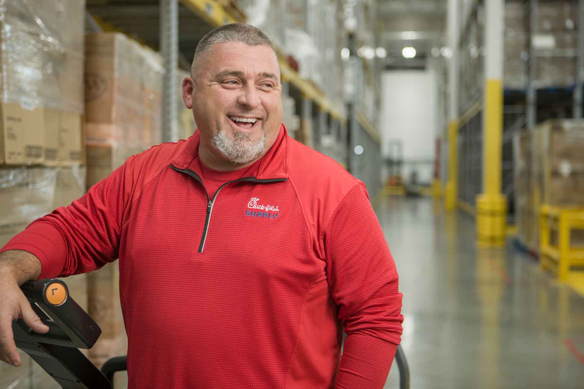 Smiling Chick‑fil‑A Supply® employee standing in a warehouse