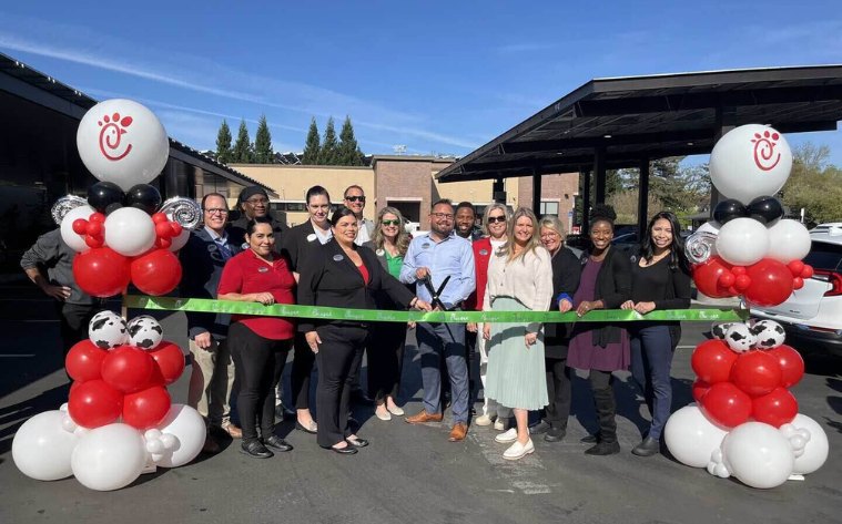 A group of people standing outside of a Chick-fil-A Microgrid Pilot Location and cutting a large ribbon